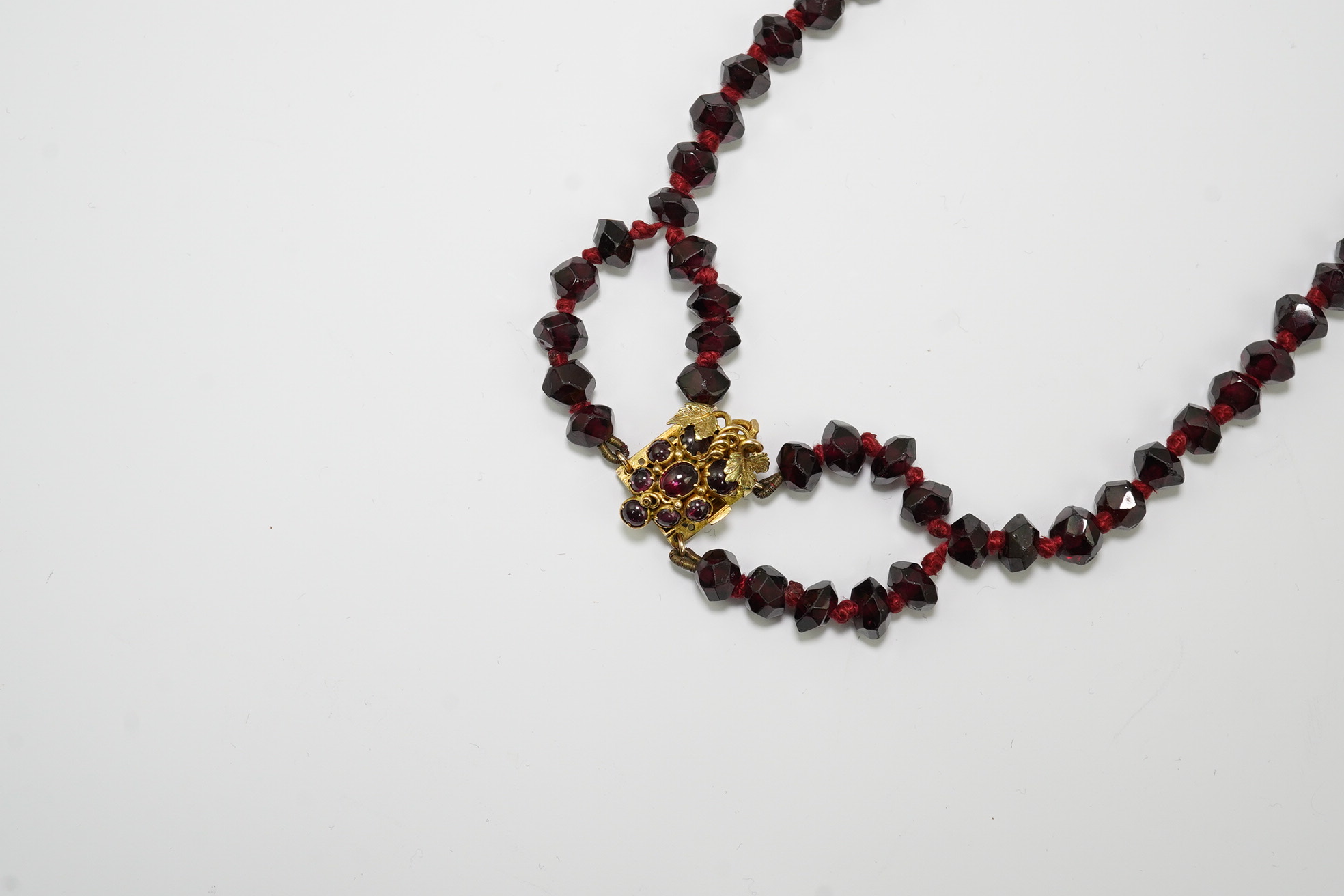 A Victorian facet cut garnet necklace, with cabochon garnet cluster set gold clasp